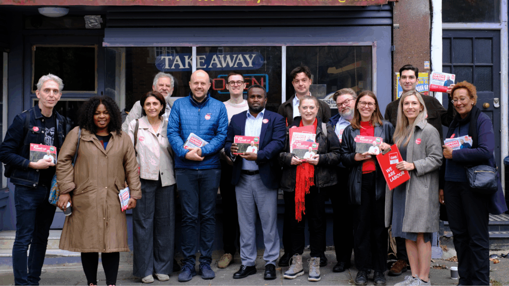 The newly elected Labour candidates standing in front of a shop with their MP, smiling and holding up leaflets